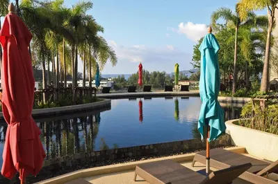 a pool with two umbrellas in front of it at 3 bdr SeaView Apartment walking to Surin Beach by CapitalPro in Phuket Town