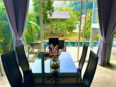 a glass table with a vase of flowers on it at Peaceful Retreat Villa by Nai Thon beach in Phuket Town