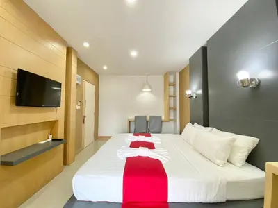 a hotel room with a large white bed with a red blanket at Chalong - Studio Service Apartment - Phoomjai in Ban Klang
