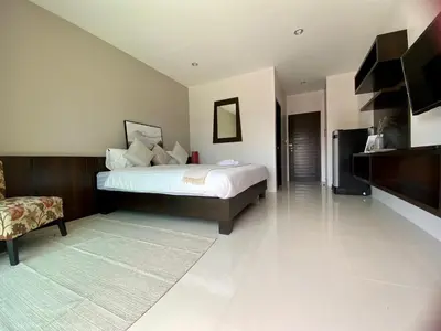 a large bedroom with a bed and a chair at SD Residence I Naiyang Beach I HKT Airport in Nai Yang Beach
