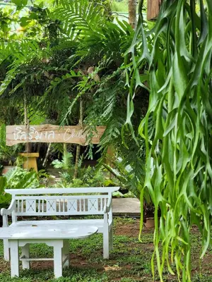 a white bench in a garden with a sign at Baan Panwa Resort in Panwa Beach