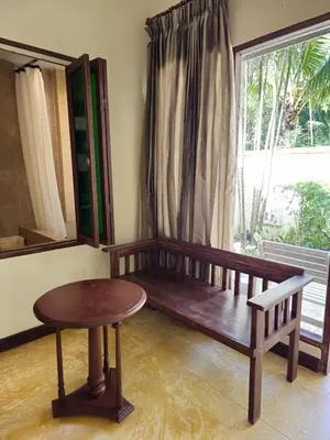 a room with a bench and a table and a window at Baan Panwa Resort in Panwa Beach