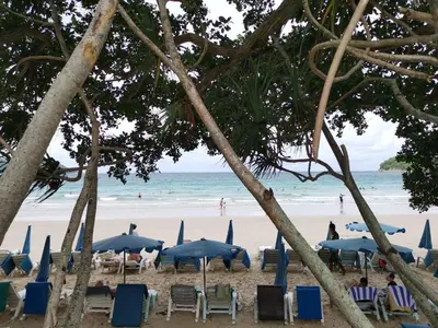 a beach with chairs and umbrellas and the ocean at 7 Floor - Ozone Condotel near Kata beach by 15 minutes walking in Kata Beach