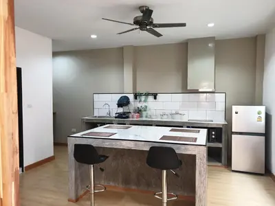 a kitchen with a large island with two bar stools at My Friend's House Villa in Karon Beach