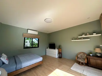 a bedroom with a bed and a tv and a window at Liang's Home เหลียงโฮม in Ban Riang
