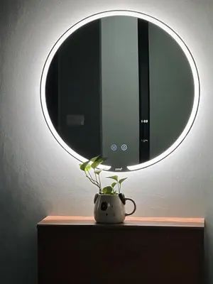 a circular mirror above a vase with a plant on a table at Liang's Home เหลียงโฮม in Ban Riang