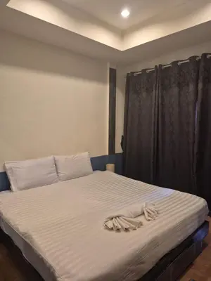 a bed with white sheets and a black curtain at Beachwalk Patong in Patong Beach