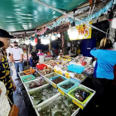 a group of people standing around a fish market at The Title V Condos by Gregory in Rawai Beach