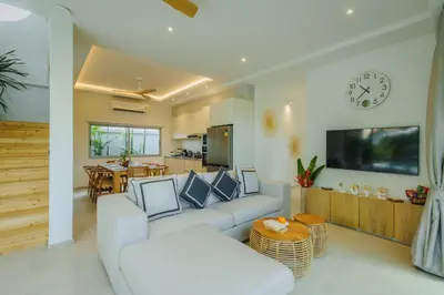 a living room with a white couch and a clock at Modern Rustic 4 Bedrooms Villa, Walk to Rawai & Yanui Beach in Nai Harn Beach