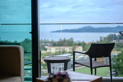 a table and chairs on a balcony with a view of the water at Уютные апартаменты в Mide Grant in Phuket Town