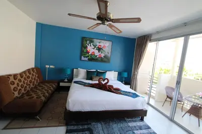 a bedroom with a bed and a couch and a ceiling fan at Sleep Easy in Kata Beach