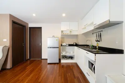 a kitchen with a white refrigerator and a wooden floor at New Apartment TTL B209 in New Rawai Beach Residence with Tropical Pools in Rawai Beach