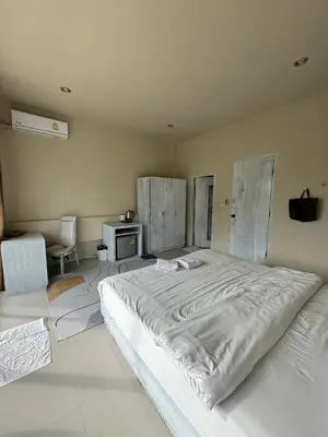 a large white bed in a room with a desk at TIL DAWN Phuket in Karon Beach