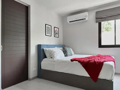 a bedroom with a bed with a red blanket on it at Great Hill Cozy Stay Pool Gym Naiyang in Phuket Town
