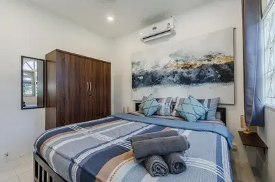 a bedroom with a blue and white bed with a painting on the wall at Karon Beach Holiday Home 1 in Karon Beach