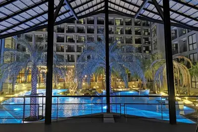 a large pool with palm trees in front of a building at Kamala Beach P55 Exclusive Junior Suite in Kamala Beach