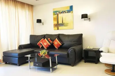 a living room with a black leather couch and a table at Luxurious 3BR Penthouse Jacuzzi Seaview in Kamala Beach
