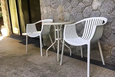 three white chairs and a table in front of a stone wall at Exquisite 3BR Private Pool Villa: Prime Location in Kamala Beach