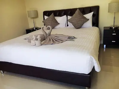 two swans are sitting on a bed with shoes at Exquisite 3BR Private Pool Villa: Prime Location in Kamala Beach