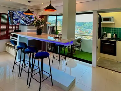 a kitchen with a bar with stools and a view at Patong Tower Holiday Rentals in Patong Beach