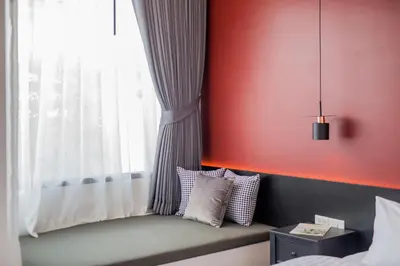 a window seat in a bedroom with a red wall at The Elements Boutique House in Phuket Town