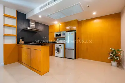 a kitchen with wooden cabinets and a washer and dryer at The Unity and The Bliss Patong Residence in Patong Beach