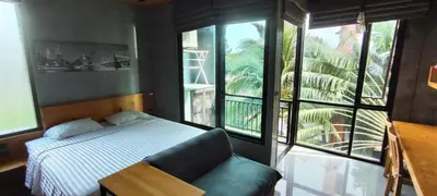 a bedroom with a bed and a chair and windows at Relife SPB in Phuket Town