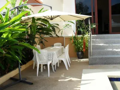 a table and chairs under an umbrella on a patio at Majestic Villas Phuket in Rawai Beach