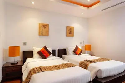 two beds in a room with white walls and orange lamps at The Residence Villa 203 in Bang Tao Beach