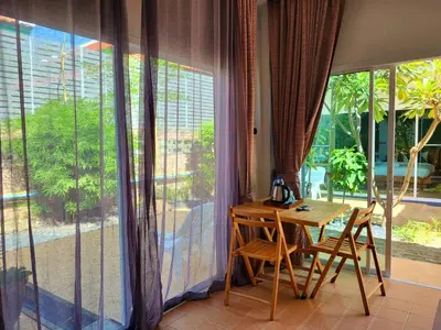 a room with a table and chairs in front of a window at Blue Palm Kata Resort in Kata Beach