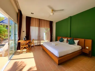 a bedroom with a bed and a green wall at Blue Palm Kata Resort in Kata Beach