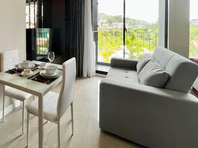 a living room with a couch and a table and a dining room at Aristo Resort Surin Beach M18 in Phuket Town
