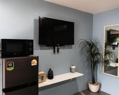 a black refrigerator and a flat screen tv on a wall at Apollo Hotel Chalong in Ban Suan