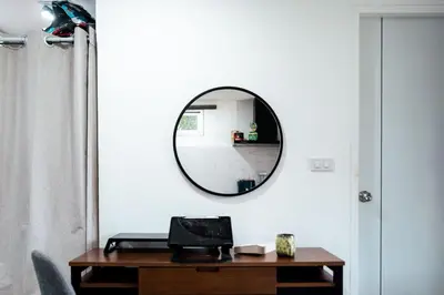 a mirror on a wall next to a table at Apollo Hotel Chalong in Ban Suan