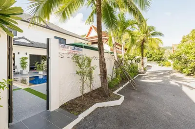a house with palm trees in front of a driveway at Kamala - Holiday Home - Studio Pool Access Bungalow in Kamala Beach