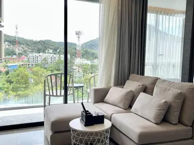 a living room with a couch and a large window at Kamala Beach P73 Exclusive Junior Suite in Kamala Beach