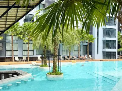 a large swimming pool with a palm tree in front of a building at Kamala Beach P73 Exclusive Junior Suite in Kamala Beach