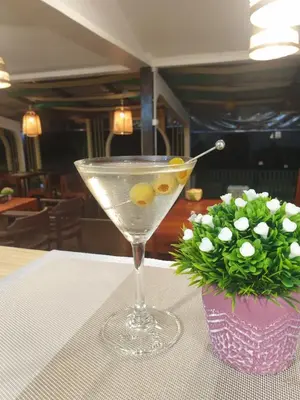 a martini glass on a table with a vase of flowers at PAN Beachfront Resort Krabi in Klong Muang Beach
