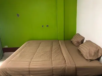 a bed in a room with a green wall at Lucky Guest House in Phi Phi Don