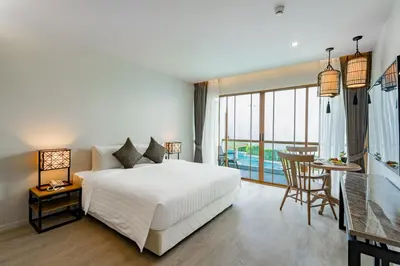 a bedroom with a white bed and a table and chairs at Bella Nara Phuket Naiyang Beach in Nai Yang Beach