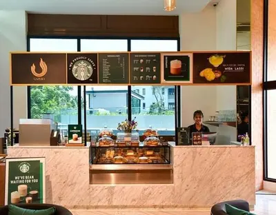 a woman sitting at a counter in a bakery at Luxury sea view apartment at Mida Grande Surin in Surin Beach