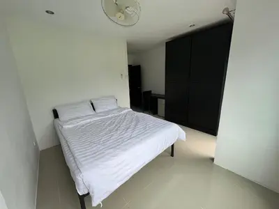 a white bed in a room with a black cabinet at Patong Easy Life 6 in Patong Beach