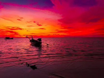 a boat on the water with a sunset at Bell Lifestyle Hostel Phuket in Nai Yang Beach