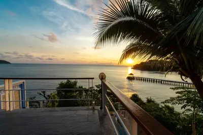 a sunset from a balcony with a view of the ocean at Villa Serenity pool SeaView 6BR in Kamala Beach