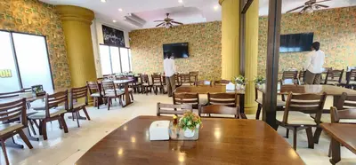 a restaurant with wooden tables and chairs and people in the background at Royal Sweet Hotel in Patong Beach