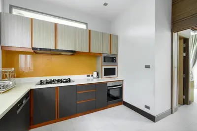 a kitchen with wooden cabinets and a stove top oven at Villa Pattara Rawai in Ban Saiyuan (1)