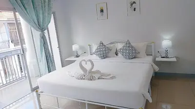 a white bedroom with two beds with a ribbon on them at Cinderella Residence in Patong Beach