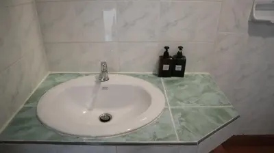a white sink in a bathroom with two bottles of soap at Patong Triple P in Patong Beach
