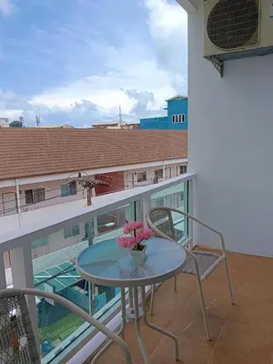 a glass table on a balcony with a vase of flowers at T & C Hotel Patong Beach in Patong Beach