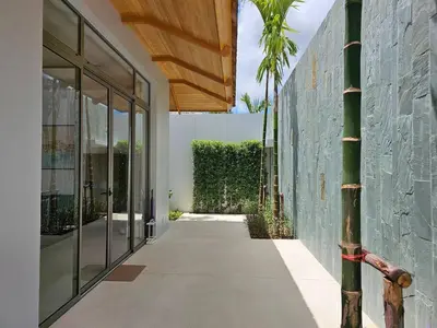 a hallway leading to a building with a palm tree at Private pool villa 3 Bed, 3 Bath near airport in Phuket Town